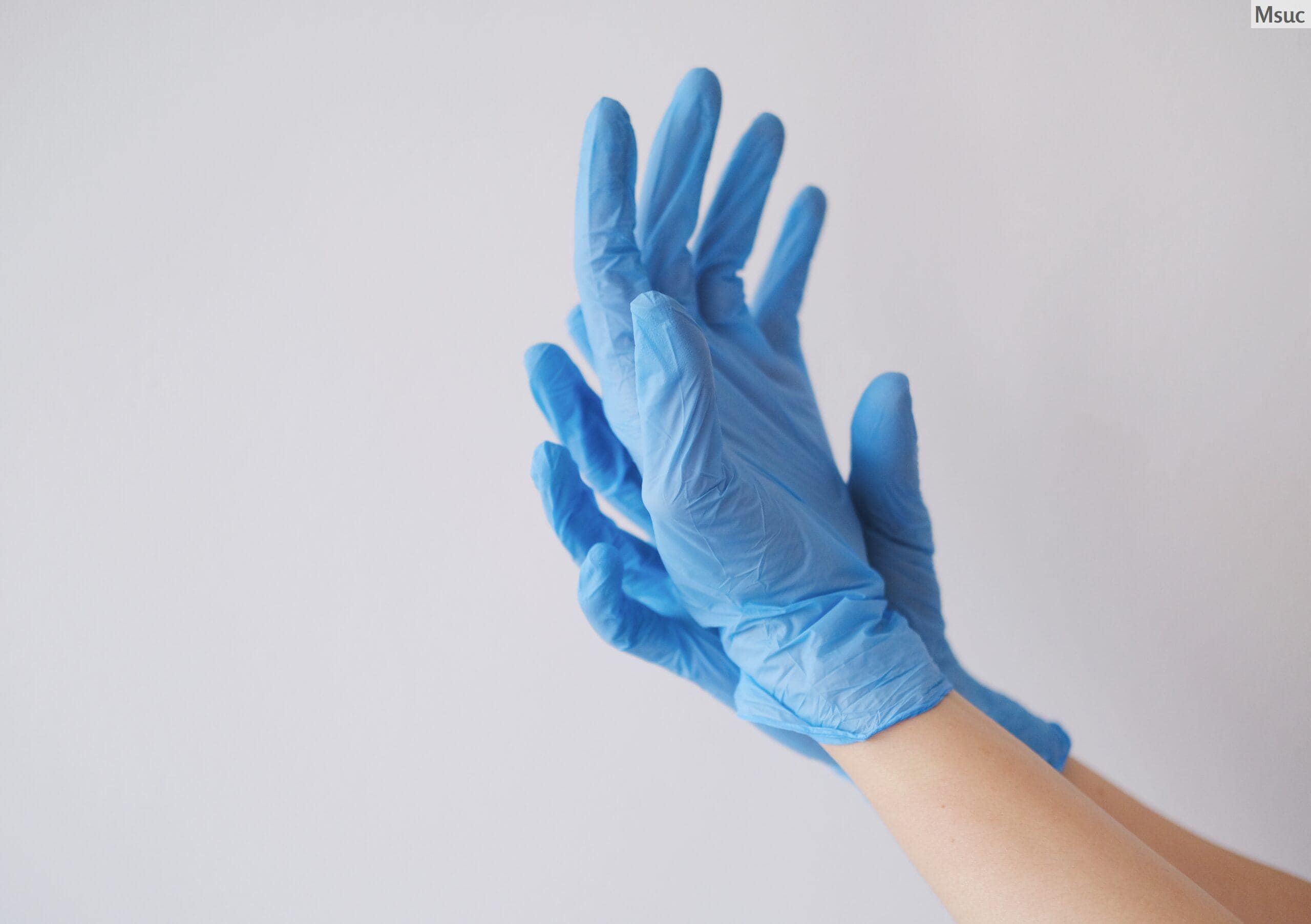 A closeup shot of a person's hands wearing blue gloves to raise awareness about the current pandemic situation