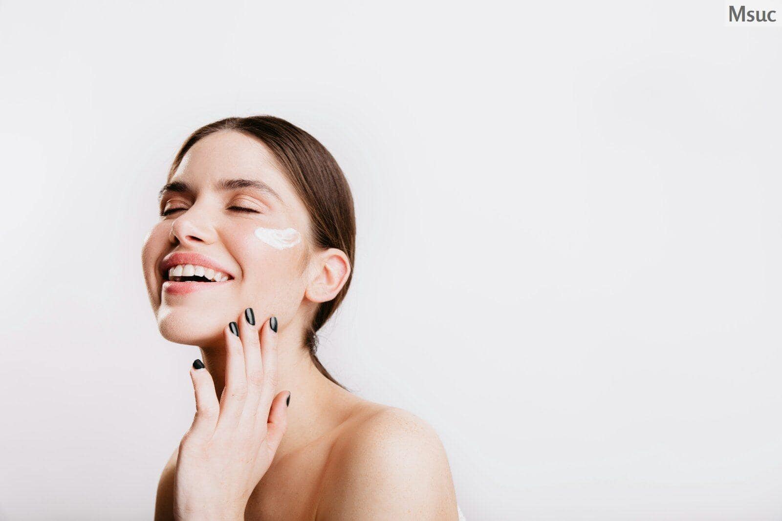 A woman smiles while she holds her hand to her face
