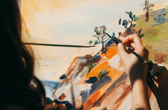 Persona pintando con pincel sobre un lienzo con paisaje