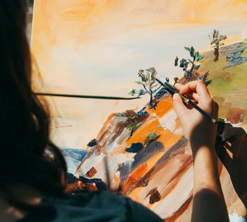 Persona pintando con pincel sobre un lienzo con paisaje